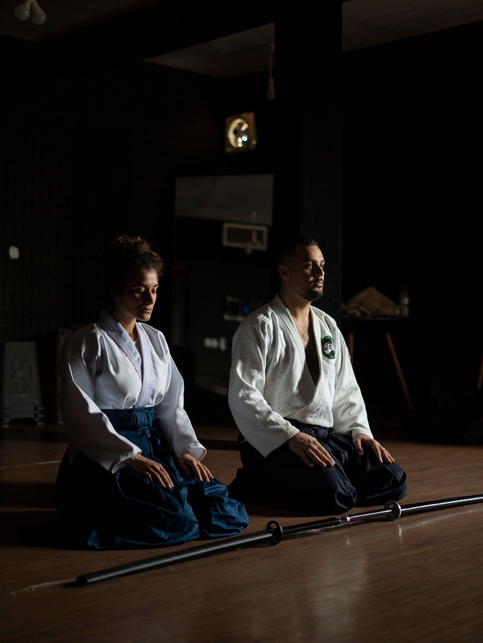 Méditation en seiza, armes en bois posées au sol, dans le dojo