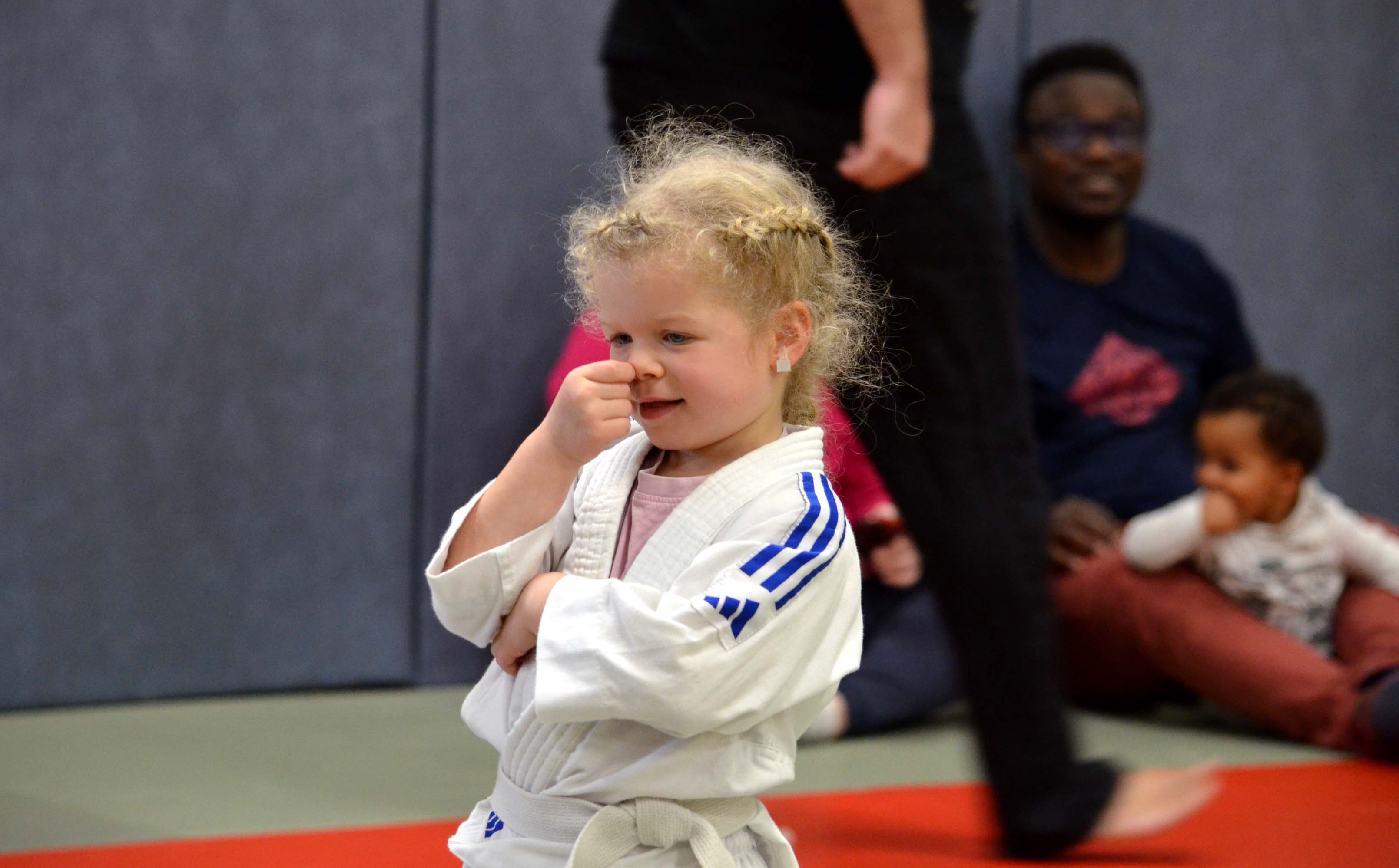 Petite fille en judogi, poing levé, fière après son cours de baby judo