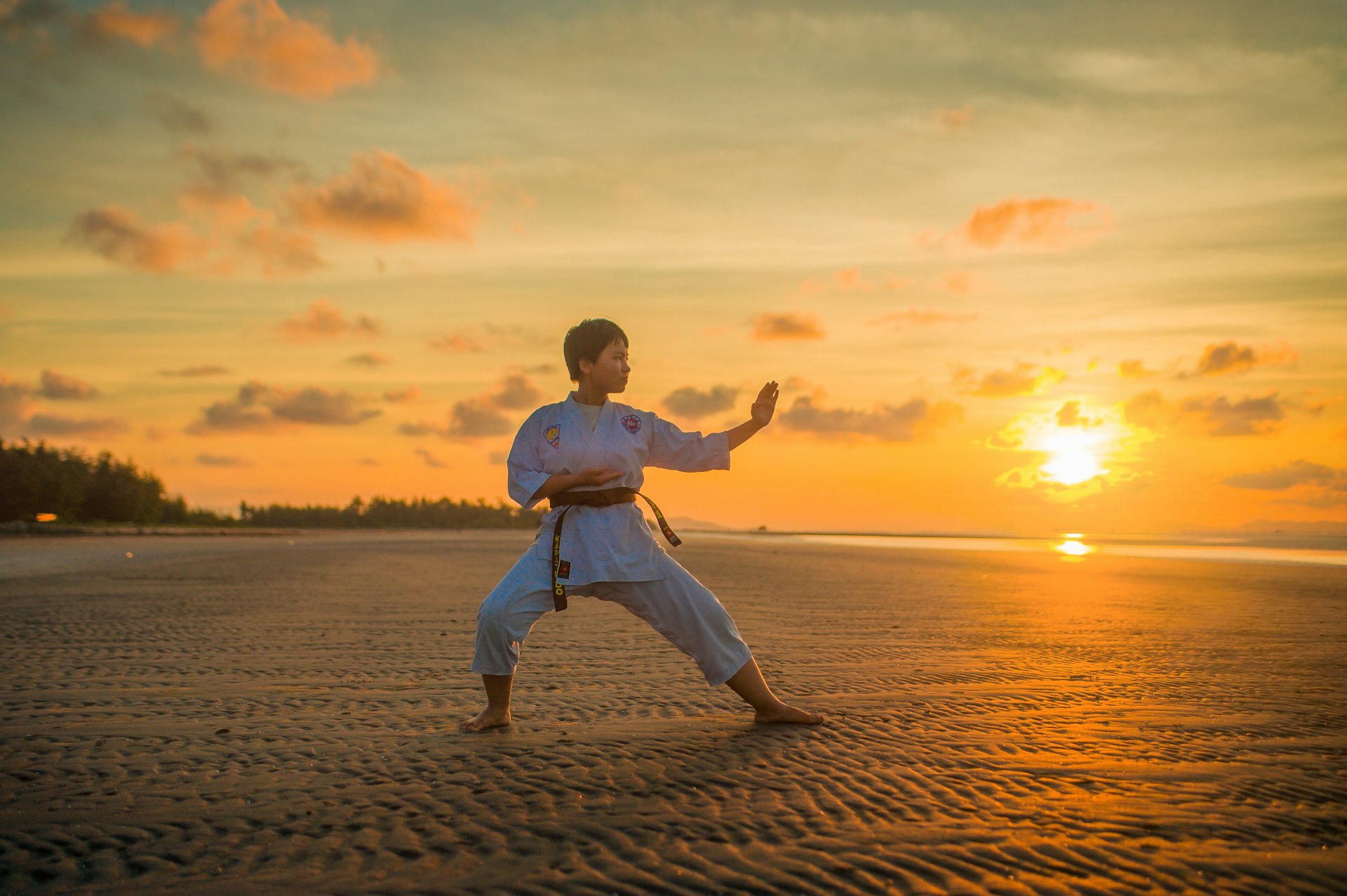 Karatéka exécutant un kata sur la plage au coucher de soleil